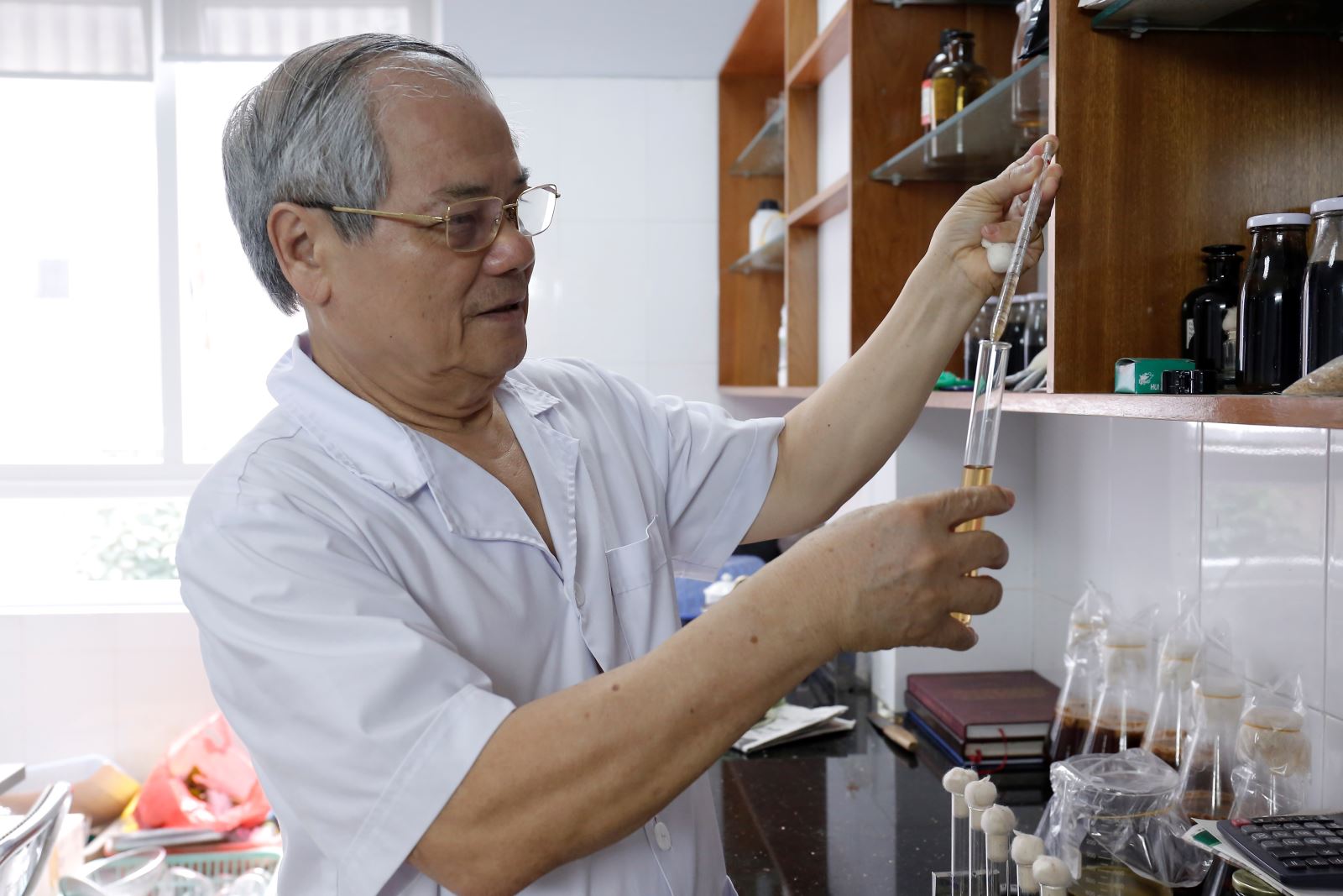 TS. Lê Văn Tri đang thử nghiệm cách pha chế nước khử trùng từ tinh dầu theo đặt hàng của một doanh nghiệp. Ảnh: Thanh An